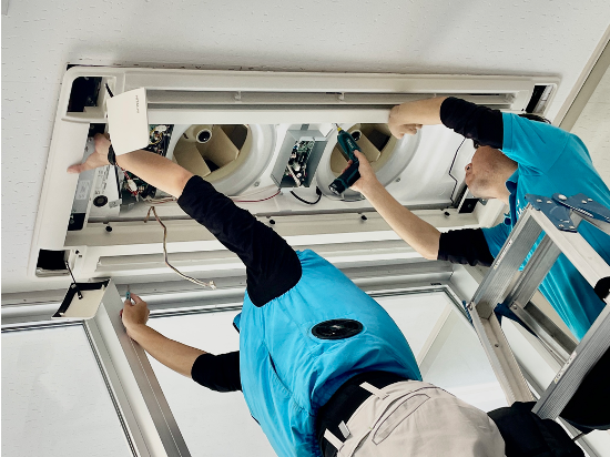 1台のエアコンを2名で清掃する様子